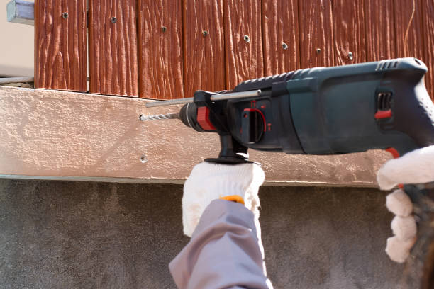 Man hand holding and using electric drill at cement wall. Maintenance concept.