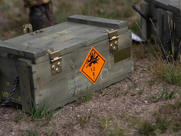 Military ammunition crate with explosive warning label positioned on ground with vegetation